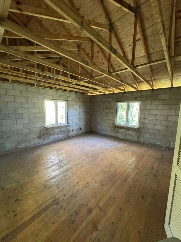 Ceiling and finishes demolished to expose the roof trusses and original subfloor, with the block walls left structurally sound.