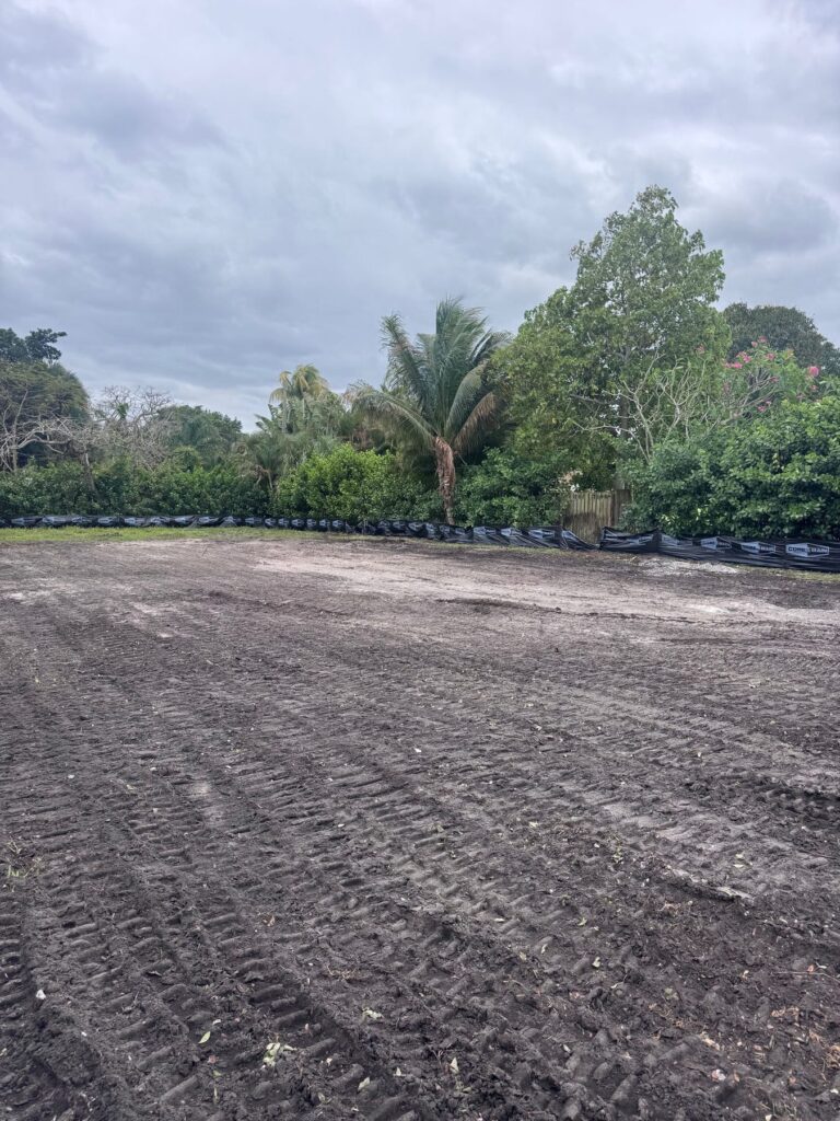 Cleared and graded lot with silt fencing run along the tree line after site clearing and debris haul off.