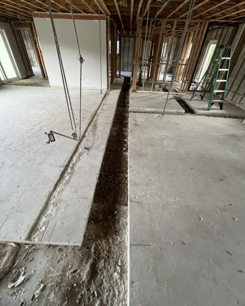 Saw cut trench running through a concrete slab for a new plumbing line, cut clean with the surrounding slab undamaged.