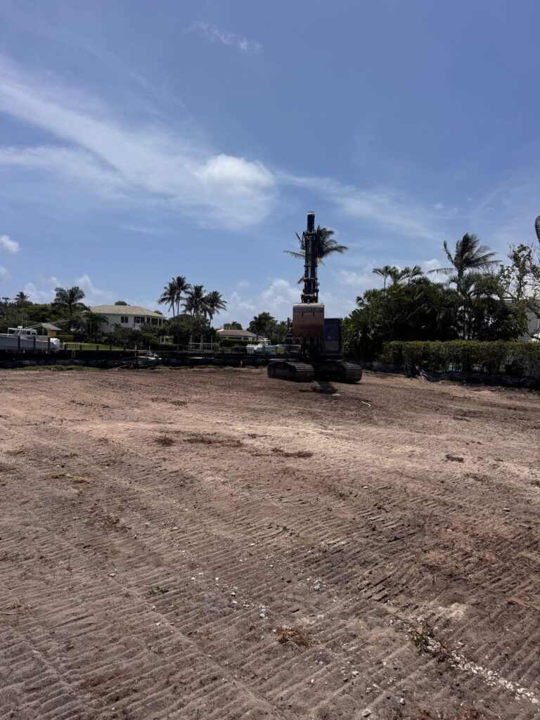 Excavator working a cleared residential lot, graded flat with the debris hauled off the site.